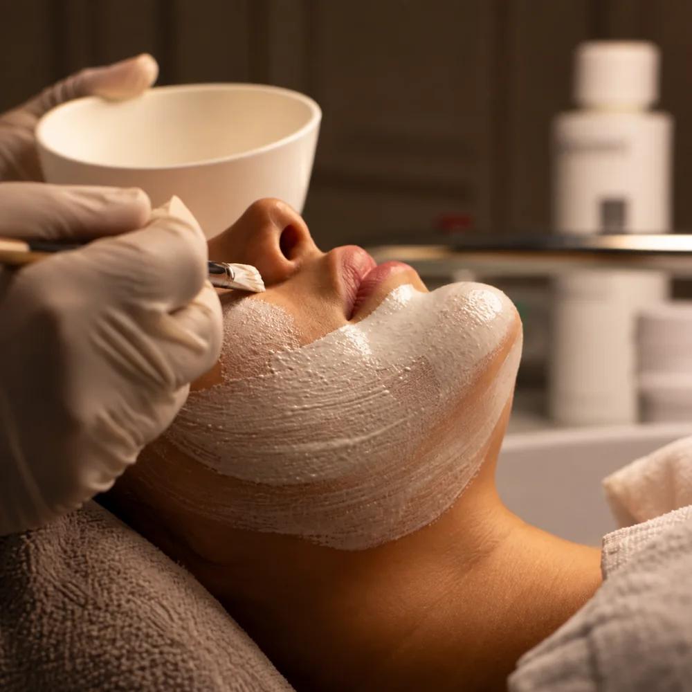 A creamy facial mask being brushed on