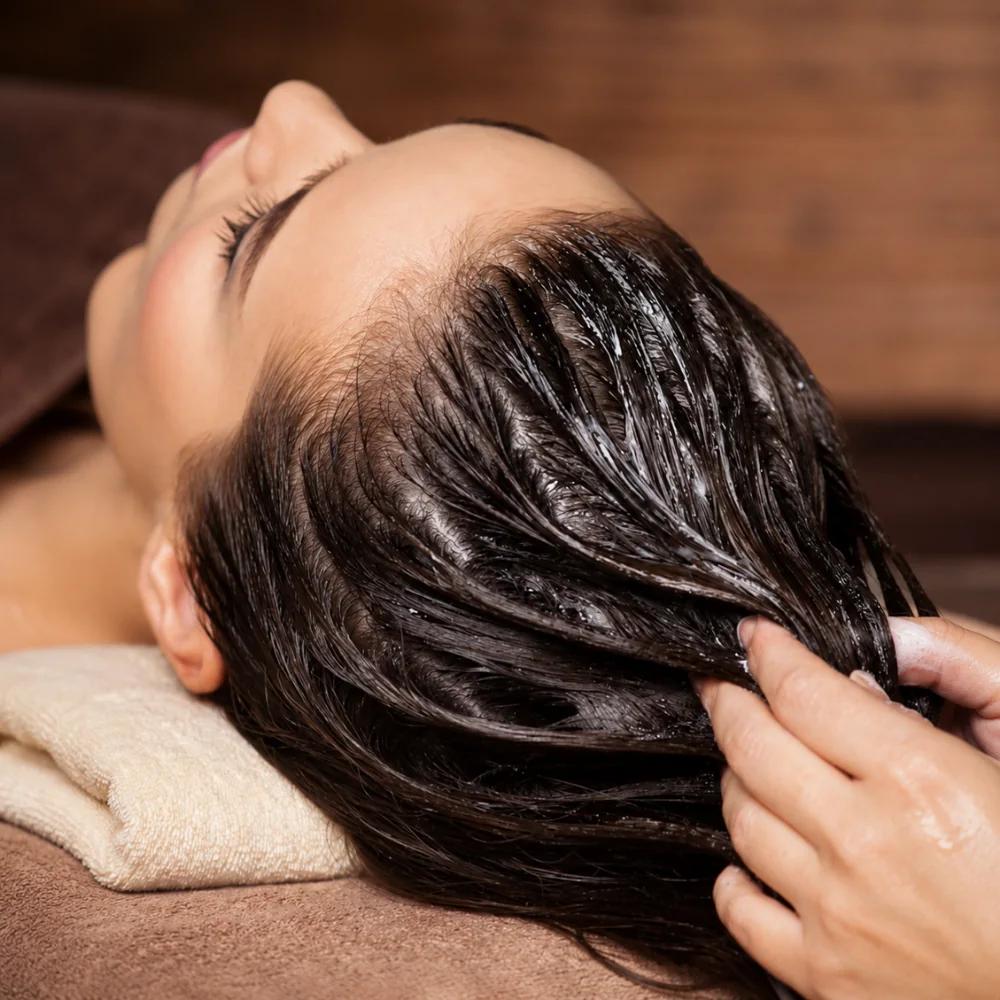 A nourishing mask being worked through long dark hair